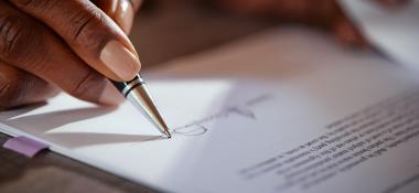 Closeup of a person signing a form